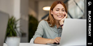 Donna sorridente seduta a una scrivania guarda lo schermo di un portatile, con etichetta Black Friday 2025 sulla destra