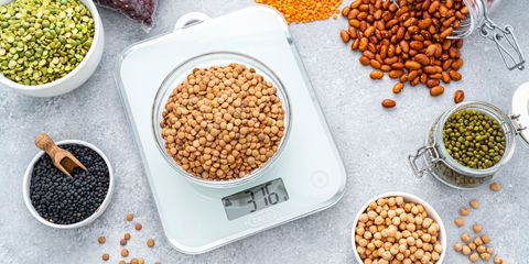 Bilancia elettronica in vetro per cucina di design, con display digitale, utilizzata per pesare legumi secchi in ciotole e barattoli.
