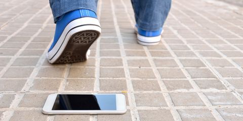 smartphone smarrito sul pavimento della strada con gambe di uomo che si allontanano sullo sfondo
