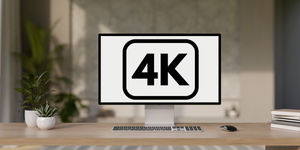 Monitor con scritta 4K su scrivania ordinata, accanto sono presenti due piantine