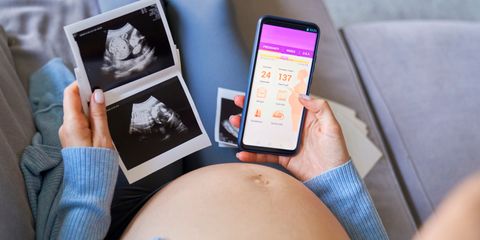 Donna incinta osserva ecografie in bianco e nero mentre controlla sullo smartphone un’app per il monitoraggio della gravidanza.