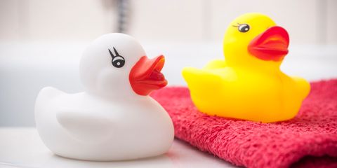 Due paperelle di gomma, una bianca e una gialla, su un asciugamano rosso in bagno