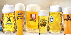 Sei bicchieri di birra chiara bavaresi dell'Oktoberfest con abbondante schiuma, servite in boccali e calici con loghi tradizionali Paulaner, Spaten, Augustiner, Loewenbrau, HB e Hacker-Pschorr
