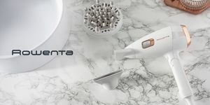 Asciugacapelli Rowenta ScalpCare Ultimate Experience bianco con inserti dorati appoggiato su piano in marmo, affiancato da beccuccio e diffusore intercambiabili.