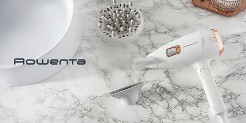 Asciugacapelli Rowenta ScalpCare Ultimate Experience bianco con inserti dorati appoggiato su piano in marmo, affiancato da beccuccio e diffusore intercambiabili.