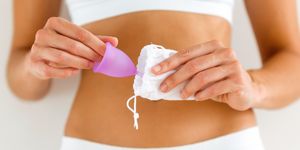 Donna che ripone una coppetta mestruale viola in un sacchetto bianco