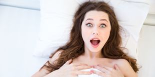 Ragazza sdraiata nel letto che mostra sorpresa