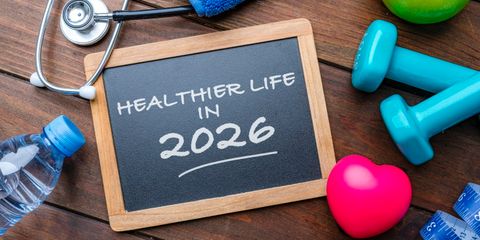 Lavagnetta con scritta sul benessere nel nuovo anno, circondata da pesi, frutta, bottiglia d’acqua e accessori per il fitness