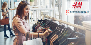 Donna che guarda vestiti appesi a delle grucce in un negozio d'abbigliamento