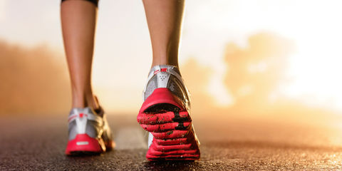 Scarpe da running indossate sull'asfalto con tramonto sullo sfondo